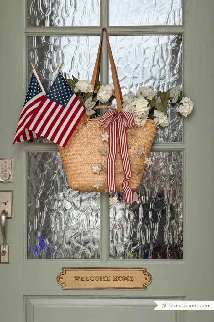 Front Door Patriotic Decor, Tote Basket Filled With White Flowers, American Flags. Red and White ribbon with Glitter Star Garland, Welcome Home Plaque, Sage Green Painted Front Door